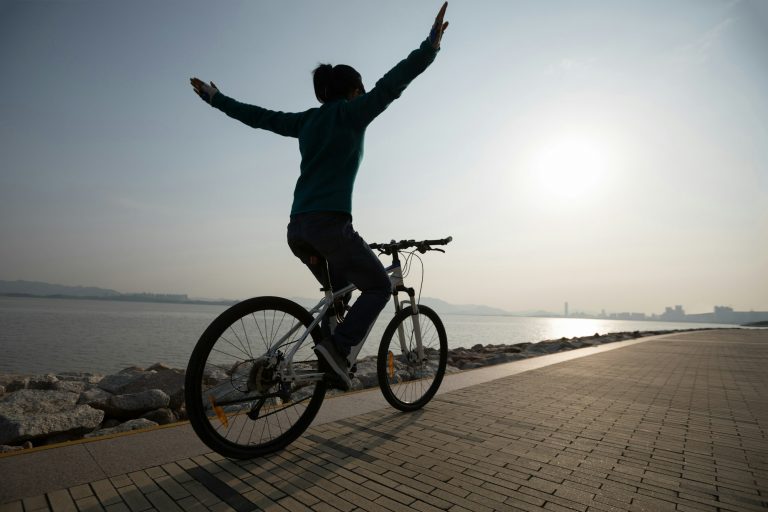 Person fährt Fahrrad mit ausgestreckten Armen, um das Makemore Bike-Leasing-Programm zu genießen.